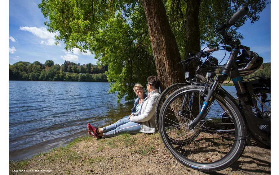 Zwei Frauen mit ihren Rädern machen eine Pause am Seeufer