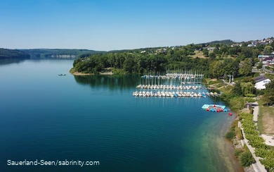 Drohnenaufnahme vom glasklaren blauen Wasser mit Segelbooten im Hintergrund